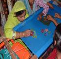 Woman stitching a decorative pattern on blue fabric