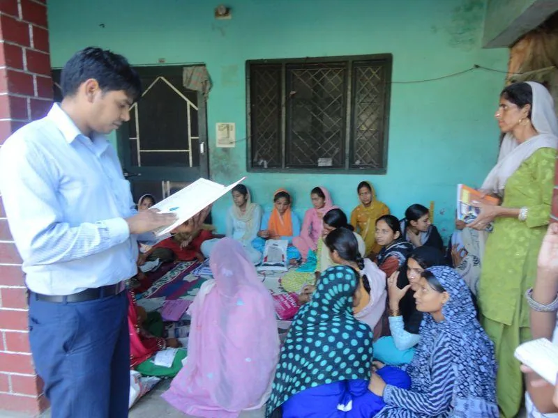 Programme facilitator discussing materials with women during a community visit