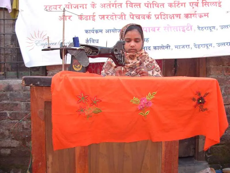 Woman displaying embroidered fabric beside a sewing machine